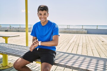 Young hispanic man training using smart watch outdoors