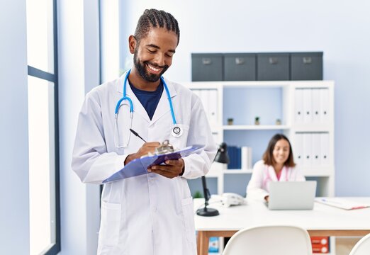 Man and woman wearing doctor uniform smiling confident working at clinic