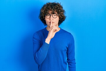 Fototapeta na wymiar Handsome young man wearing casual clothes and glasses asking to be quiet with finger on lips. silence and secret concept.