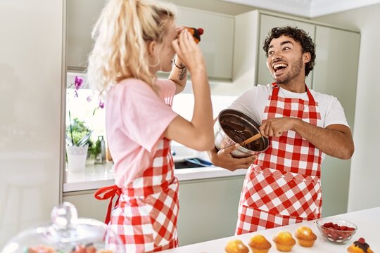 Young couple smiling happy cooking sweets holding pumpkin on eyes at kitchen.