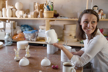 the girl artist enamels handmade wooden toys in an art workshop