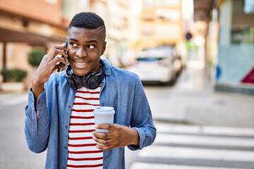 Young african american man talking on the smartphone drinking coffee at the city.