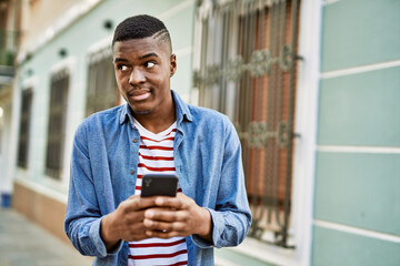 Young african american man smiling happy using smartphone at the city.