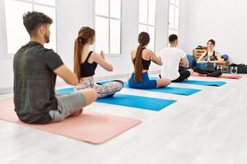 Group of young people having yoga class with personal trainer at sport center.