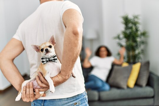 Man surprising his wife with adorable dog at home. - Powered by Adobe