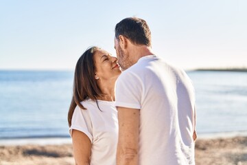 Middle age man and woman couple standing together kissing at seaside