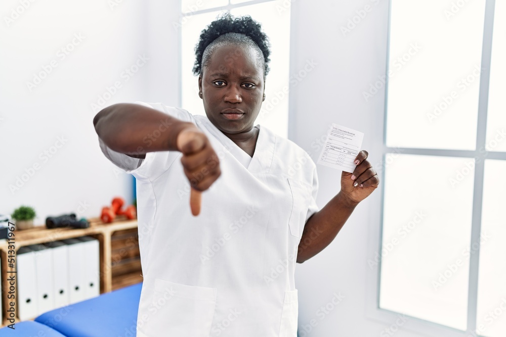 Sticker young african woman holding covid record card at clinic with angry face, negative sign showing disli