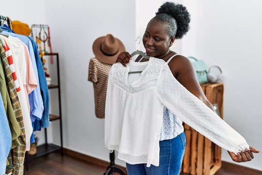 Young african american woman customer holding clothes of rack at clothing store