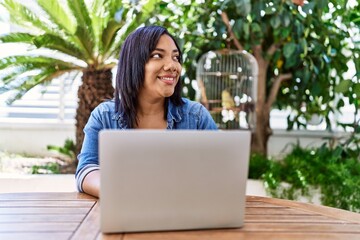 Hispanic brunette woman using laptop at the terrace