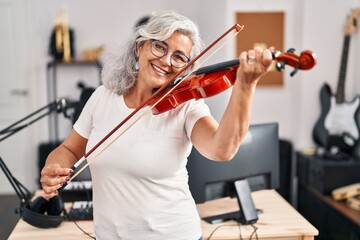 Middle age woman musician playing violin at music studio © Krakenimages.com