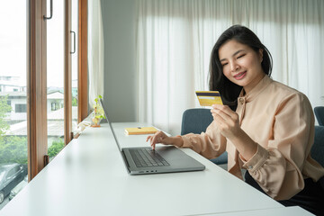 Young woman holding credit card and using laptop computer. Online shopping concept