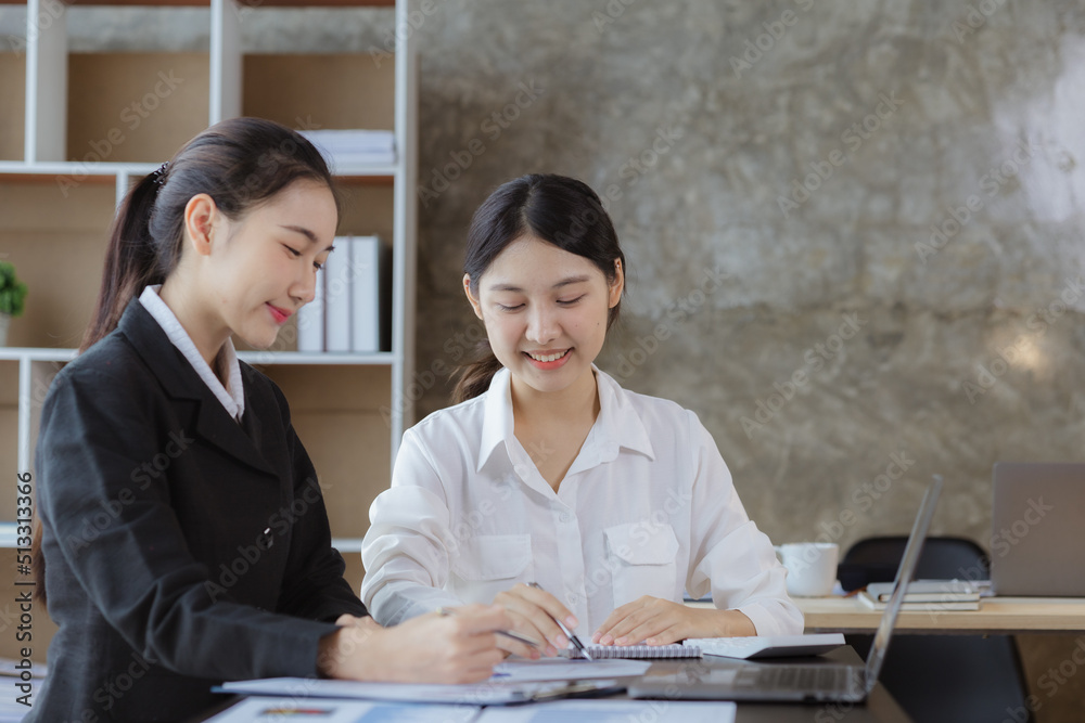 Wall mural atmosphere in the office of a startup company, two female employees are discussing, brainstorming id