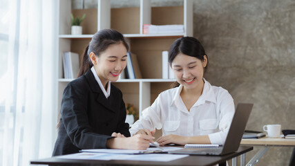 Atmosphere in the office of a startup company, two female employees are discussing, brainstorming ideas to working on summaries and marketing plans to increase sales and prepare reports to managers.
