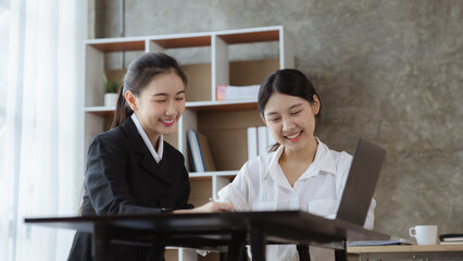 Atmosphere in the office of a startup company, two female employees are discussing, brainstorming ideas to working on summaries and marketing plans to increase sales and prepare reports to managers.