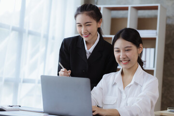Obraz premium Atmosphere in the office of a startup company, two female employees are discussing, brainstorming ideas to working on summaries and marketing plans to increase sales and prepare reports to managers.