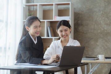 Atmosphere in the office of a startup company, two female employees are discussing, brainstorming ideas to working on summaries and marketing plans to increase sales and prepare reports to managers.