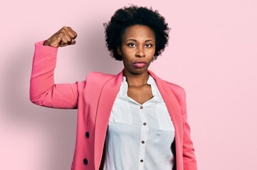 African american woman with afro hair wearing business jacket strong person showing arm muscle, confident and proud of power