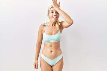 Young caucasian woman wearing bikini over isolated background surprised with hand on head for...