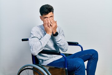 Young hispanic man sitting on wheelchair rubbing eyes for fatigue and headache, sleepy and tired...