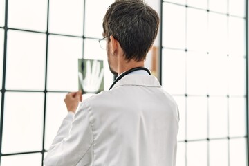 Young hispanic doctor man holding xray working at clinic