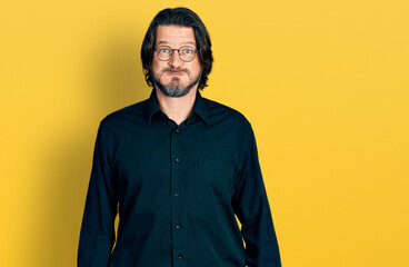 Middle age caucasian man wearing casual clothes and glasses puffing cheeks with funny face. mouth inflated with air, crazy expression.