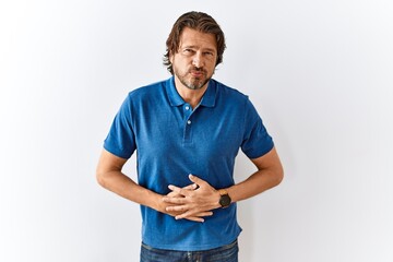 Handsome middle age man standing together over isolated background with hand on stomach because...