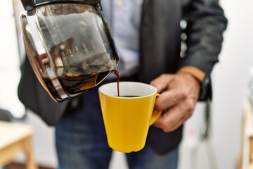 Middle age caucasian man pouring coffee on cup at office