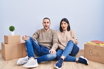 Young couple moving to a new home afraid and shocked with surprise and amazed expression, fear and excited face.