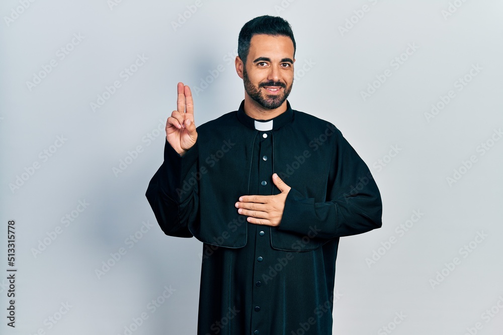 Canvas Prints Handsome hispanic man with beard wearing catholic priest robe smiling swearing with hand on chest and fingers up, making a loyalty promise oath