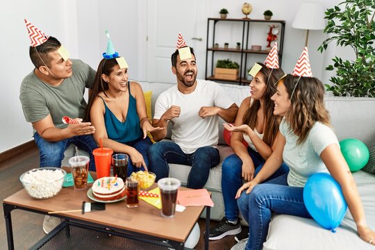 Group of young hispanic friends having birthday party playing funny game at home.