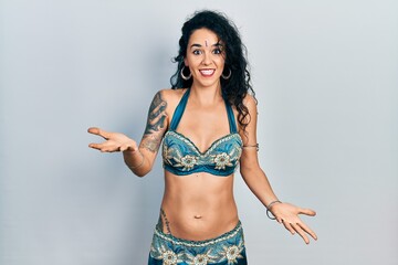 Fototapeta premium Young woman wearing bindi and traditional belly dance clothes smiling cheerful with open arms as friendly welcome, positive and confident greetings