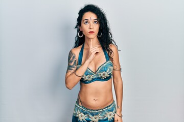 Young woman wearing bindi and traditional belly dance clothes thinking concentrated about doubt with finger on chin and looking up wondering - obrazy, fototapety, plakaty