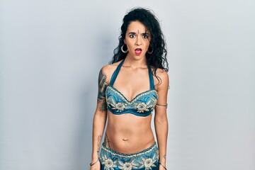 Young woman wearing bindi and traditional belly dance clothes in shock face, looking skeptical and sarcastic, surprised with open mouth