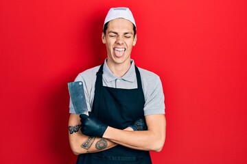 Young hispanic man wearing professional apron holding knife celebrating crazy and amazed for...
