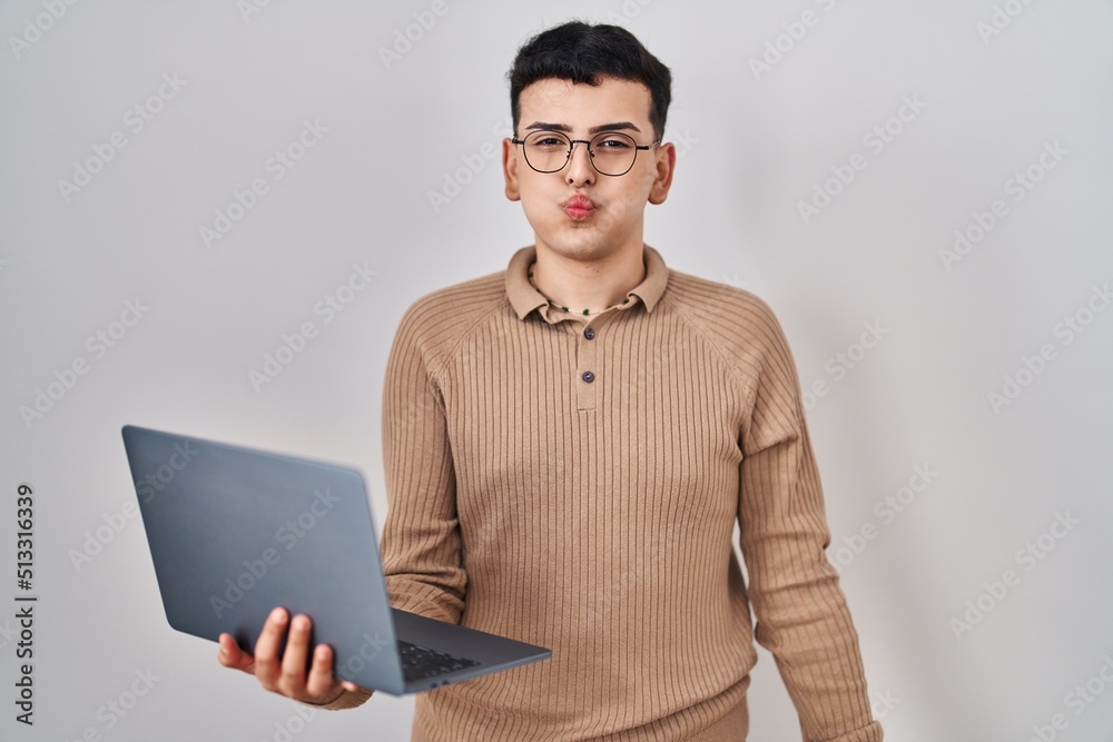 Poster Non binary person using computer laptop puffing cheeks with funny face. mouth inflated with air, crazy expression.