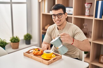 Fototapeta na wymiar Young man having breakfast sitting on table at home