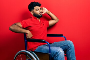 Arab man with beard sitting on wheelchair stretching back, tired and relaxed, sleepy and yawning for early morning