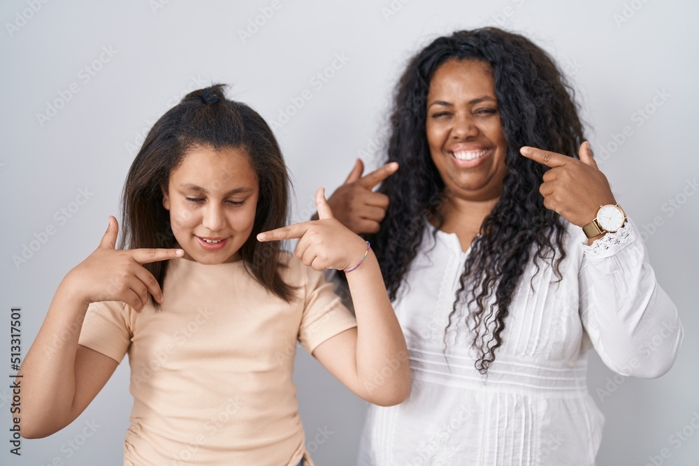 Sticker Mother and young daughter standing over white background smiling cheerful showing and pointing with fingers teeth and mouth. dental health concept.