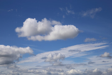 Dramatic blue clear summer sky background, white fluffy cumulus cloud over sea of cirrus clouds