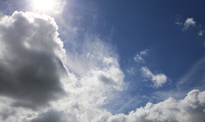 Dramatic blue clear summer sky after rain background, sun breaking through white fluffy cumulus morning clouds