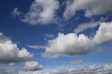 Blue clear summer sky background, high fluffy fine weather summer cumulus clouds, day sunlight