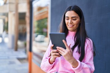 Young hispanic woman smiling confident using touchpad at street