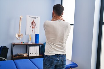 Young hispanic man injured physiotherapy patient suffering for neck ache at rehab clinic