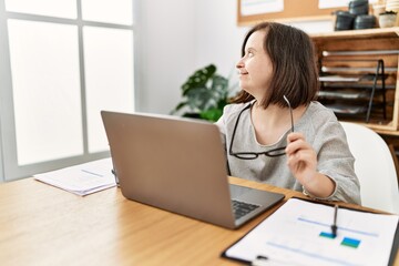 Brunette woman with down syndrome working using laptop at business office