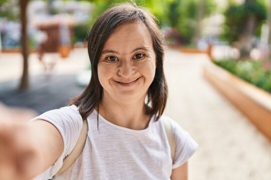 Down syndrome woman smiling confident making selfie by the camera at park