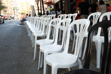 Photos of plastic chairs placed in the street, so that people can sit and watch the parade of the Alicante's fogueres festivities.