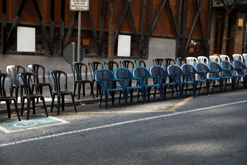 Photos of plastic chairs placed in the street, so that people can sit and watch the parade of the...