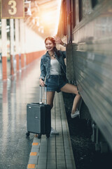 Young asian female traveler in blue jeans and luggage stepping on the train to travel alone.