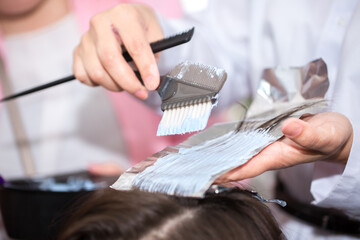 Hairdresser stylist takes care of girl's hair. Hair care procedures in a beauty salon. Hair treatment, coloring and styling. Botox and hair lamination keratin straightening.