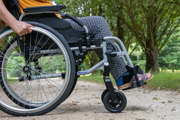 Obraz premium Close-up of a wheelchair in profile, a young woman sitting on it, in the middle of nature